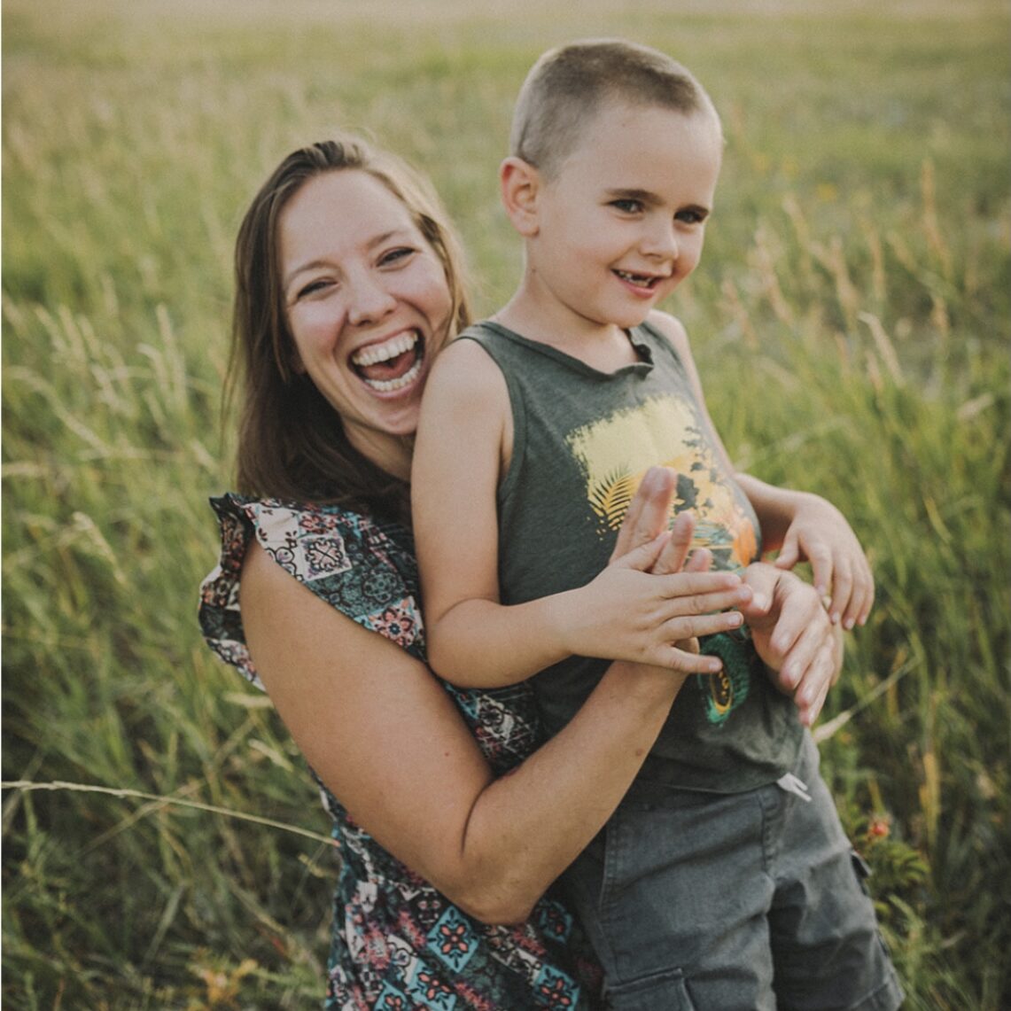 Woman smiling with toddler son in her arms, in a field