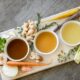 bone broth in white bowls on cutting board with vegetables